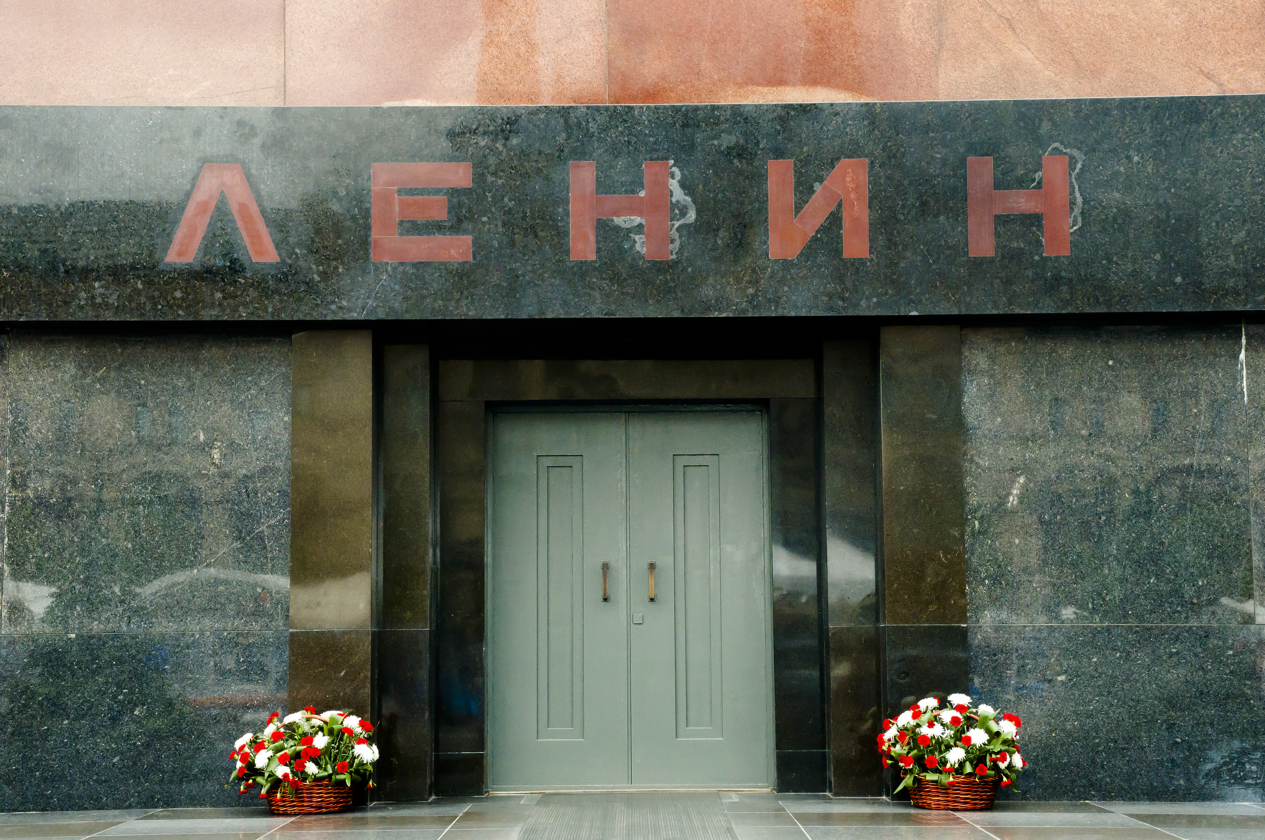Вход в Мавзолей Ленина с надписью на граните и корзинами цветов