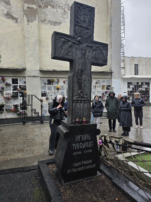 Гид с небольшой группой у чёрного гранитного памятника на Ваганьковском кладбище