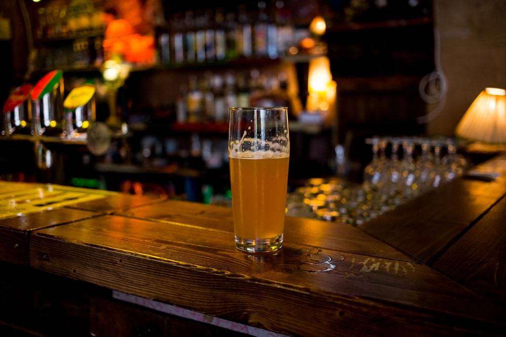 Glass of light beer on a dark pub